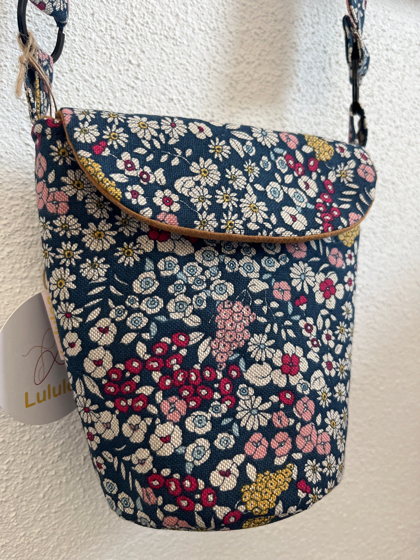 Schultertasche mit Blumen auf blauem Hintergrund